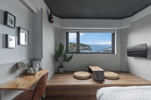 a bedroom with a desk and a window and a bed at Jiufen The Ocean Theory in Jiufen