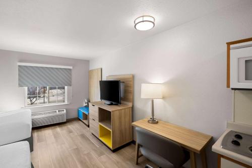 a hotel room with a desk with a bed and a television at Birch Hill Suites Rochester - Med City in Rochester