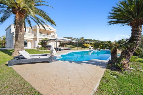 une villa avec piscine et palmiers dans l'établissement Panorama d'Exception Piscine Chauffée proche de la mer dans un Domaine privée, à Grimaud