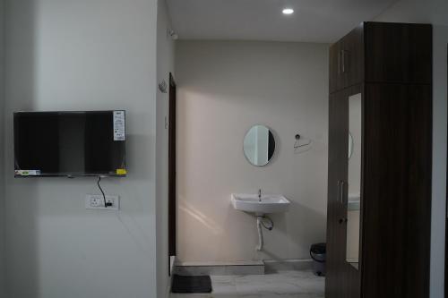 baño con lavabo y TV en la pared en Dwaraka Heaven Luxury rooms, en Kondapur