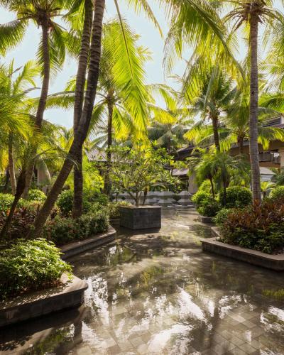 a garden with palm trees and a pond at Raffles Hainan Clear Water Bay in Sanya