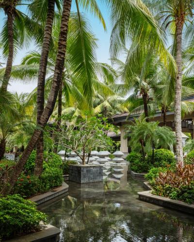 a garden with palm trees and a pond at Raffles Hainan Clear Water Bay in Sanya