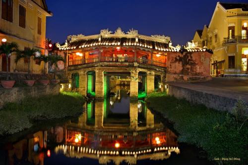 a building with a reflection in the water at night at Dong Nguyen Riverside Homestay in Hoi An