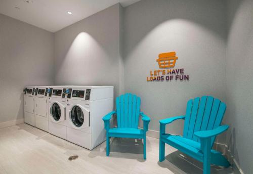 two blue chairs and a washing machine in a laundry room at Home2 Suites By Hilton Lumberton in Lumberton