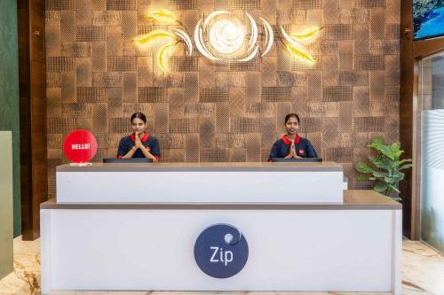 two men standing behind a reception desk at Zip By Spree Hotels Ranjangaon in Ranjangaon Ganpati