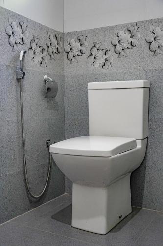 a white toilet in a bathroom with flowers on the wall at Palm & Wild Hiriketiya in Dickwella
