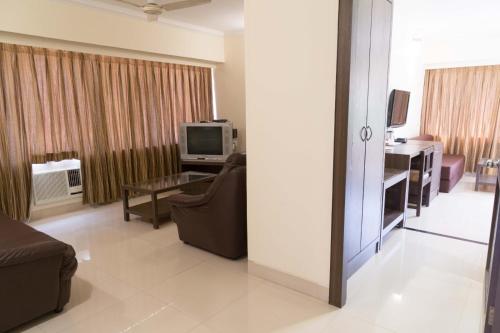 a living room with a couch and a tv at Hotel Aroma Executive Panaji -Stay in the Heart of the City in Panaji