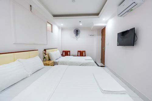 a bedroom with two beds and a tv on the wall at Light Hotel Ha Noi in Hanoi