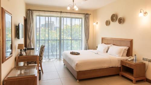 a bedroom with a bed and a desk and a window at Lotos Inn & Suites, Nairobi in Nairobi