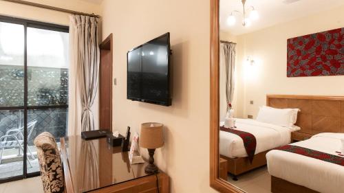 a hotel room with a bed and a television at Lotos Inn & Suites, Nairobi in Nairobi