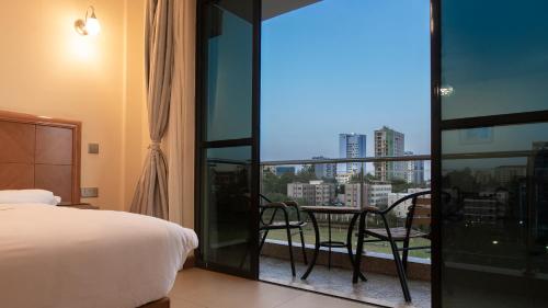 a bedroom with a bed and a balcony with a table at Lotos Inn & Suites, Nairobi in Nairobi