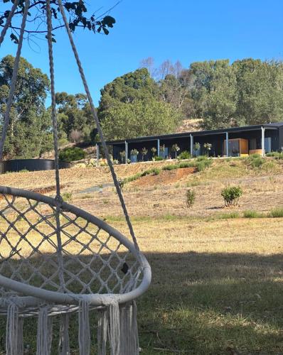 a swing in a field with a building in the background at Circle of Light Retreat in Kangaroo Gully