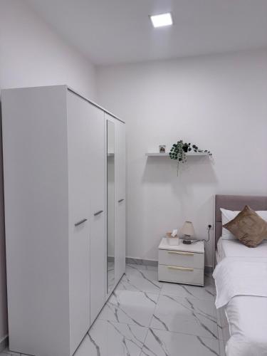a bedroom with white walls and a bed and a mirror at Le silver appartement 2 chambres in Libreville