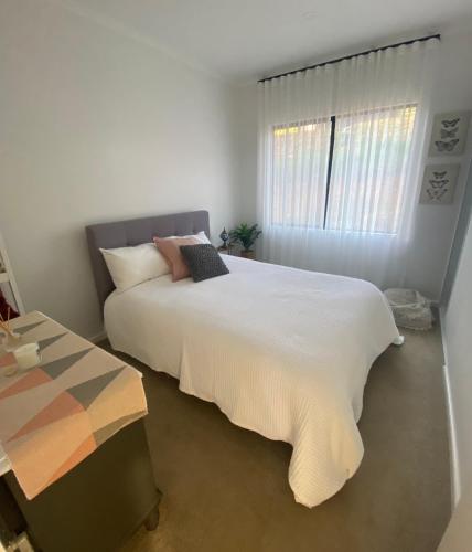 a bedroom with a large white bed and a window at Circle of Light Retreat in Kangaroo Gully