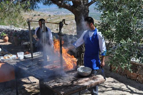 un hombre cocinando comida sobre un fuego en una parrilla en Agriturismo Avola Antica, en Avola