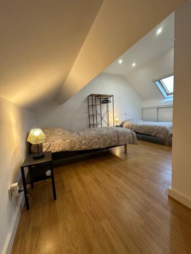 a attic bedroom with two beds and a table with a lamp at THE120 work or holiday home in Comines