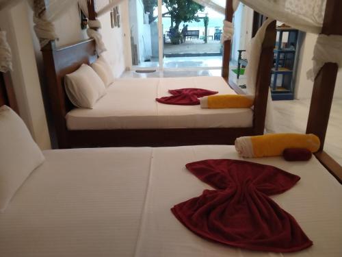 two beds in a room with red robes on them at Sea Crest Beach Villa in Ambalangoda