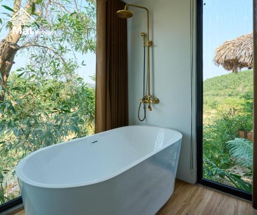 a white bath tub in front of a window at Mật Retreat in Ba Vì