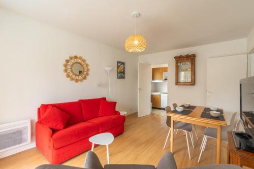 un salon avec un canapé rouge et une table dans l'établissement Le Pré Catelan, à Saint-Georges-de-Didonne