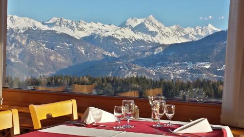 a table with wine glasses and a view of mountains at Hôtel Splendide in Crans-Montana
