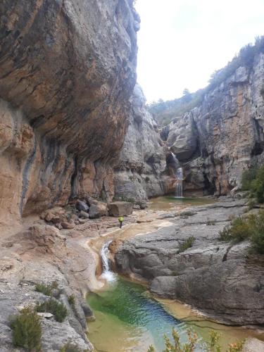 a river in a canyon with a waterfall at Hotel Guara Inlukā in Las Almunias
