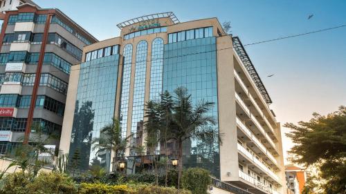 a tall glass building with palm trees in front of it at Lotos Inn & Suites, Nairobi in Nairobi