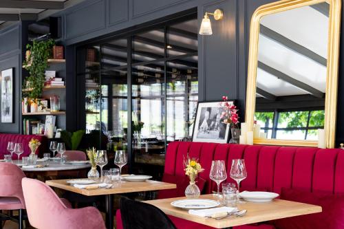 a restaurant with two tables and a red couch at Le Logis d'Origine. in Marly-le-Roi
