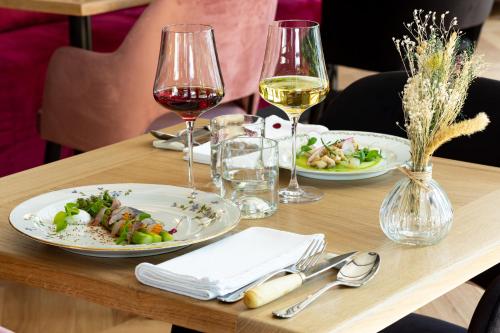 a table with two plates of food and wine glasses at Le Logis d'Origine. in Marly-le-Roi