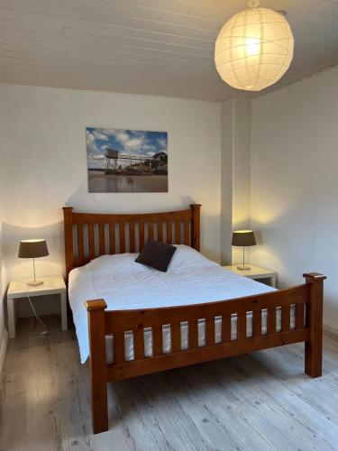 - une chambre avec un lit en bois, 2 tables et une lampe dans l'établissement Maison 47m2 meublée 200m plage, à La Bernerie-en-Retz