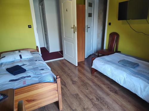 a bedroom with two beds and a tv on the wall at Lwi dworek LD in Jarosław