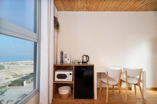 a kitchen with a table and chairs and a microwave at Dead Sea Rooftop - גג ים המלח in Ovnat