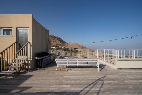 a bench sitting on a deck next to a building at Dead Sea Rooftop - גג ים המלח in Ovnat