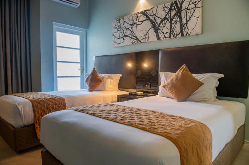 a hotel room with two beds and a window at New Ambassador Hotel in Harare