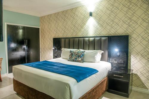 a bedroom with a large bed with a blue blanket at New Ambassador Hotel in Harare