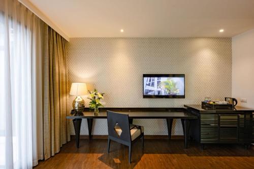 an office with a desk and a television on a wall at Mövenpick Hotel Sukhumvit 15 Bangkok in Bangkok