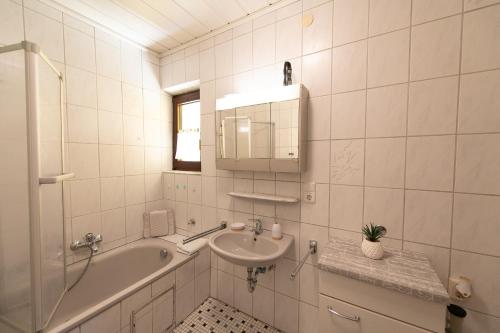 a bathroom with a sink and a bath tub and a mirror at Ferienwohnung Werner in Warmensteinach