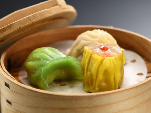 a wooden bowl of food with green peppers and cheese at 厳美渓温泉いつくし園 in Itsukushi