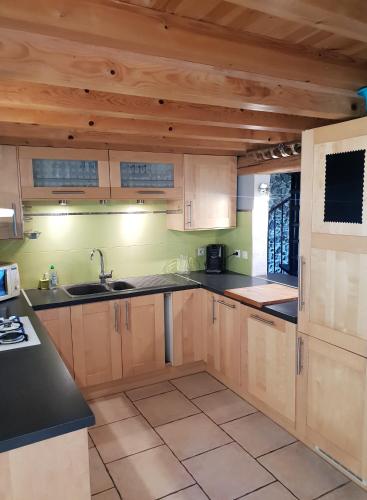 une cuisine avec des placards en bois et des comptoirs noirs dans l'établissement Le Récantou - Appartement Villelongue d 'Aude, à Villelongue-dʼAude