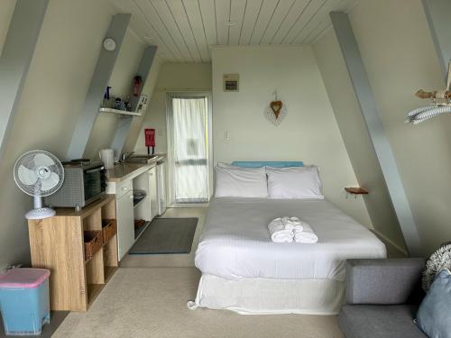 a small bedroom with a bed and a desk at Aroha A-Frames - Bush & Beach Retro Retreat in Coromandel Town