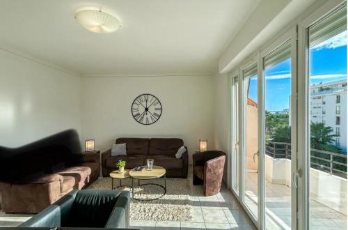 un salon avec un canapé et une horloge au mur dans l'établissement Stylish 3P, 2 pas la Croisette, à Cannes