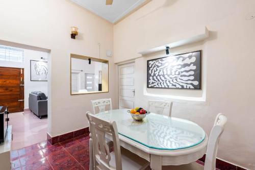 a dining room with a glass table and white chairs at Sliceinn Prasanthi 3 BHK- Indiranagar, Bangalore in Bengaluru