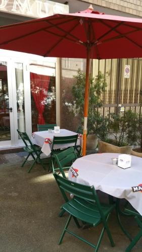 two tables and chairs under a red umbrella at Domus Hotel in Alessandria