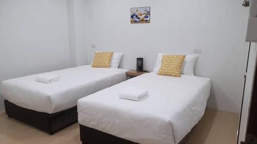 two beds sitting next to each other in a room at Sandy hotel in Krabi town