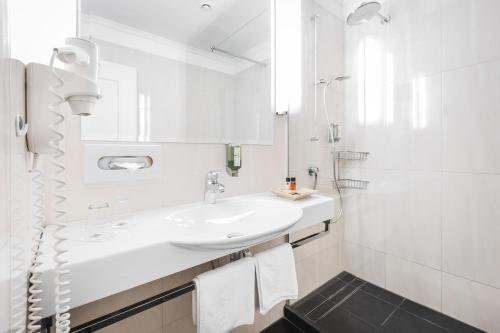 a white bathroom with a sink and a mirror at Post Seefeld - Wellnesshotel Tirol in Seefeld in Tirol