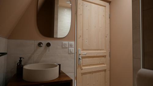 La salle de bains est pourvue d'un lavabo blanc à côté d'une porte. dans l'établissement La Kalinka Maison réconfortante au calme et proche du centre, à Saint-Brieuc