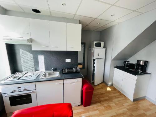 une cuisine avec des placards blancs et une chaise rouge dans l'établissement F2 Pensée, à La Bourboule