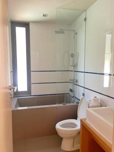 a bathroom with a toilet and a tub and a window at บ้านแสนคราม in Ban Huai Sai Tai