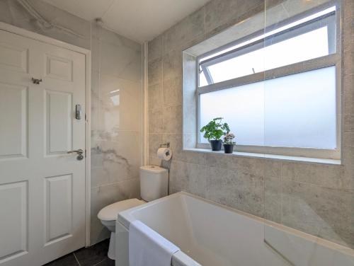 a bathroom with a tub and a toilet and a window at Modern Double Room W Private Bath & Free Parking in York