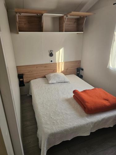 - une chambre avec un lit recouvert d'une couverture orange dans l'établissement Mobilehome cosy, à Biscarrosse