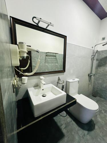a bathroom with a sink and a toilet and a mirror at Hotel Sunil's in Kataragama